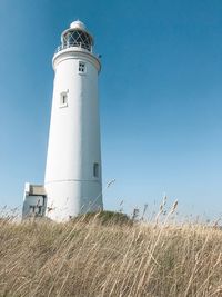 Lighthouse on field against sky