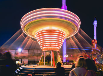 People in illuminated amusement park at night