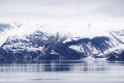 Scenic view of lake by snowcapped mountains against sky