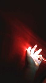 Close-up of hand against illuminated red light