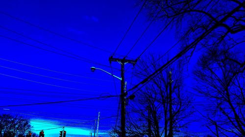 Low angle view of electricity pylon against blue sky