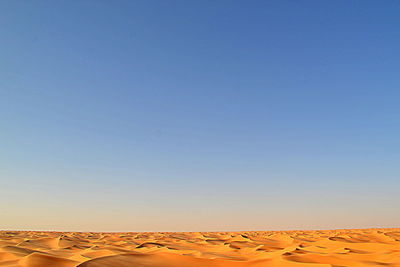 Scenic view of desert against clear blue sky