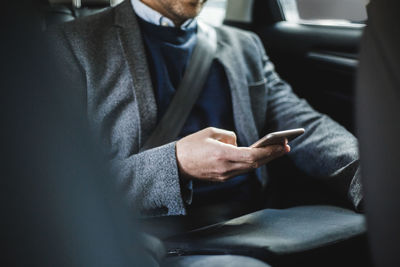 Midsection of mature businessman using phone while sitting in car