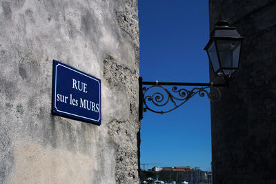 Low angle view of sign on building against blue sky