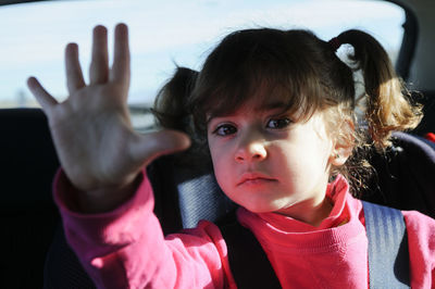 Portrait of cute girl gesturing while sitting in car