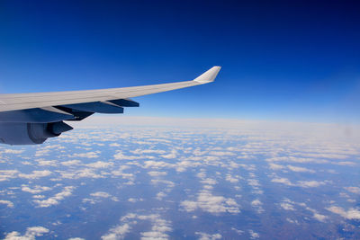 Cropped image of airplane wing against blue sky