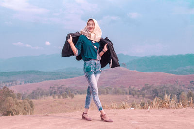 Full length of woman standing on landscape against sky