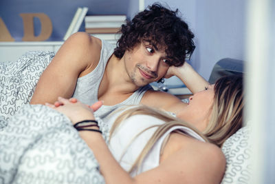 Portrait of young couple lying on bed at home