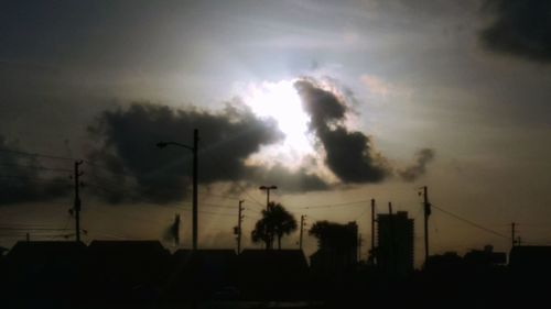 Low angle view of silhouette electricity pylon against dramatic sky