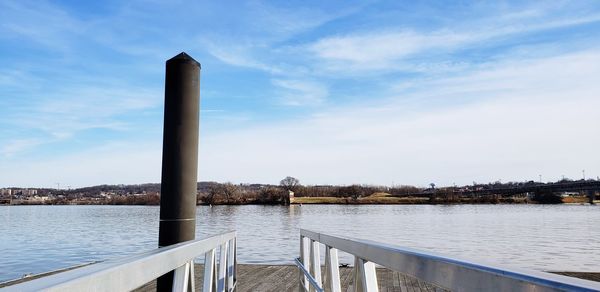 Wooden post by river against sky