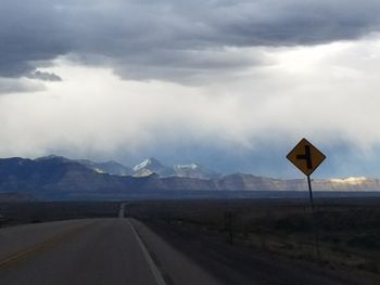 Road sign by mountains against sky