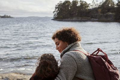 Female couple sitting by sea