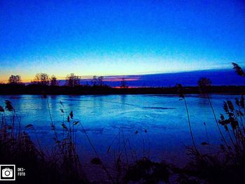 Scenic view of lake against clear blue sky at dusk
