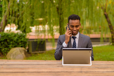 Young man using mobile phone while sitting on table