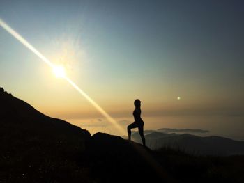 Silhouette man standing on mountain against sky during sunset