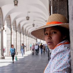Portrait of young woman wearing hat while standing in corridor