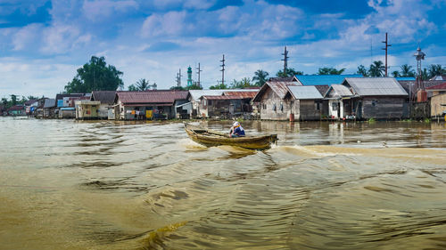 Boats on beach by buildings against sky