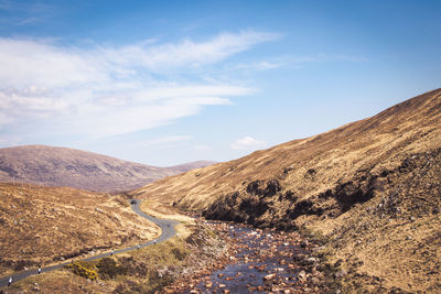 Scenic view of road by mountains against sky