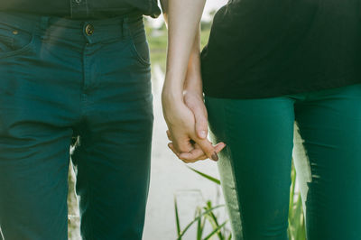 Midsection of couple holding hands