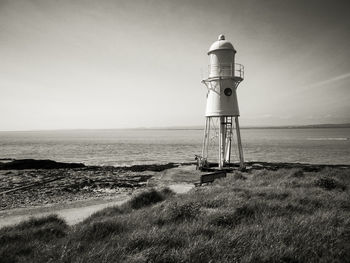 Lighthouse by sea against sky