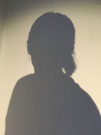 Close-up portrait of silhouette woman against wall