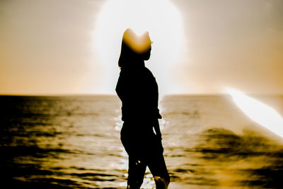 Silhouette man standing on beach against sky during sunset