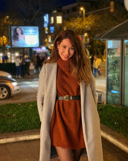 Portrait of smiling woman standing in city at night