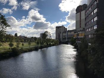 Canal in city against cloudy sky