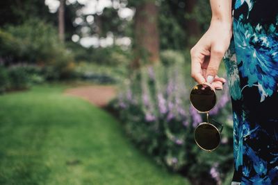 Cropped image of woman holding sunglasses at park