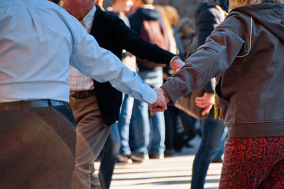 Rear view of friends standing on street holding hands while traditional dance, mallorca