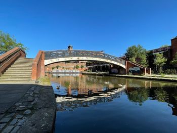 Arch bridge over canal against clear blue sky