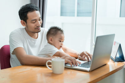 Father with son using laptop at table