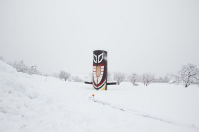 Information sign on snow covered field against sky