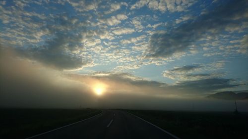 Country road against cloudy sky