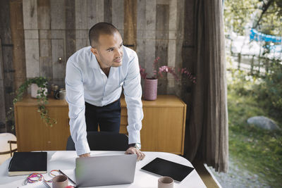 Businessman looking away while using laptop at desk in portable office truck