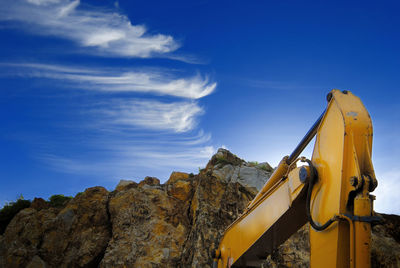 Low angle view of yellow rocks against blue sky