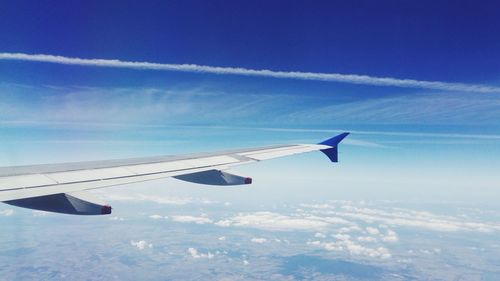 Airplane wing against cloudy sky