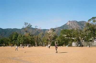 Group of people playing on mountain against clear sky