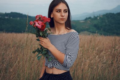 Young woman holding flowers on field