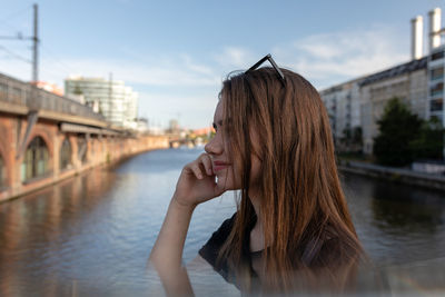 Smiling woman on bridge over river against sky