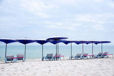 Chairs on beach against sky