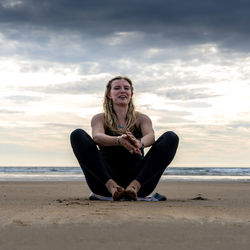 Young woman practicing yoga on the beach in newborough, north wales, uk