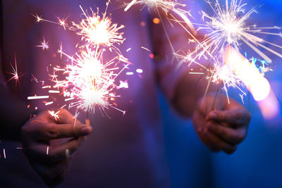 Midsection of woman holding sparklers at night