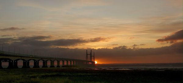 Bridge over sea against sky during sunset