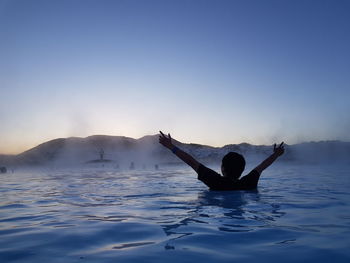 Man surfing in water against clear sky