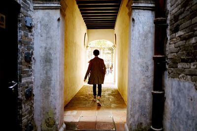 Full length rear view of man walking on narrow walkway