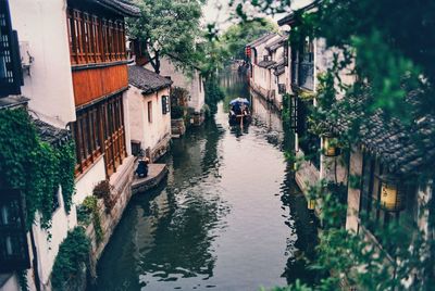 Canal amidst buildings in city during rainy season