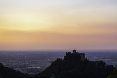 Silhouette buildings against sky at sunset