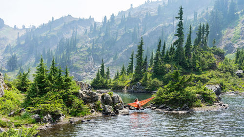 Woman is enjoying an afternoon in a hammock at the alpine lake