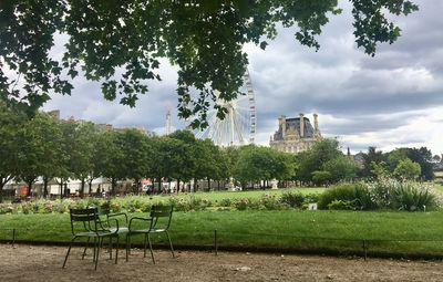 Chairs and table in park against sky